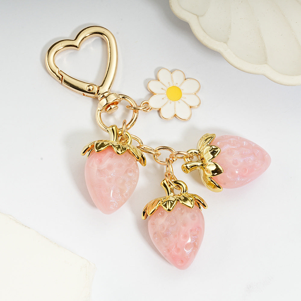 Adorable transparent strawberry keychain paired with a heart-shaped hook and daisy decorations -a sweet and stylish accessory